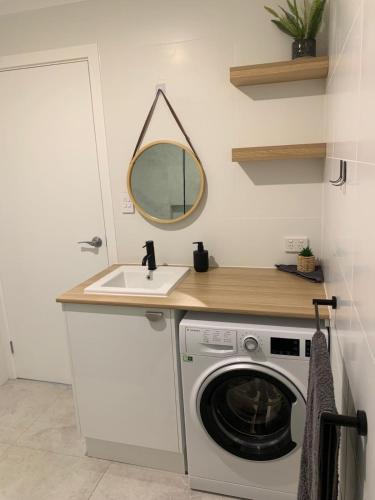 a laundry room with a sink and a washing machine at Charming 1-bed Coastal Escape at Links Lady Bay in Normanville