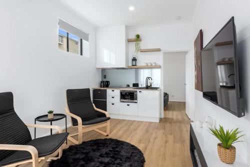 a living room with two chairs and a kitchen at Charming 1-bed Coastal Escape at Links Lady Bay in Normanville