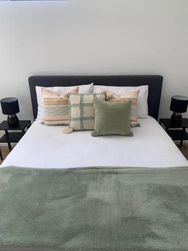 a bed with a green blanket and pillows on it at Charming 1-bed Coastal Escape at Links Lady Bay in Normanville