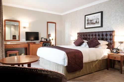 a hotel room with a large bed and a television at The Red Lion Hotel in Hillingdon