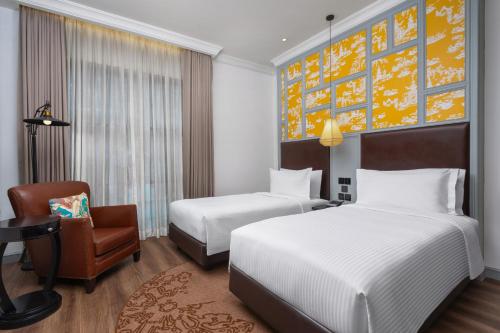 a hotel room with two beds and a chair at Metropole, Bangkok, a Tribute Portfolio Hotel in Bangkok