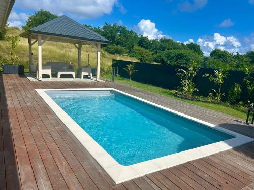 a swimming pool on a deck with a gazebo at Villa Jade , villa de standing proche de la plage in Le Vauclin