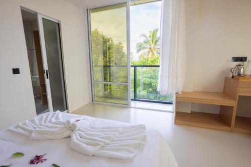 ein weißes Bett in einem Zimmer mit einem großen Fenster in der Unterkunft Aqua Luna Dhangethi in Dhangethi