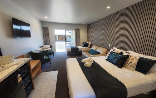 a bedroom with a large bed and a living room at Alpine Lodge Motel in Hanmer Springs