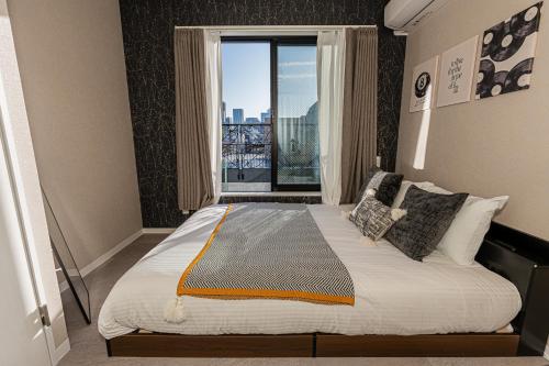 a bedroom with a large bed with a large window at Mi-Hotel Kitashinjuku 北新宿 in Tokyo