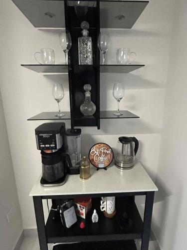 a shelf with wine glasses and a coffee maker at Bonita casa amueblada, cerca de una iglesia, playas y centros comerciales in Playa de Vacas