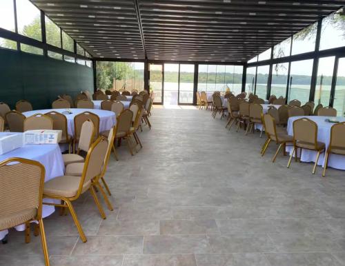 a row of tables and chairs in a room with windows at Casa Rustica Cernica in Cernica