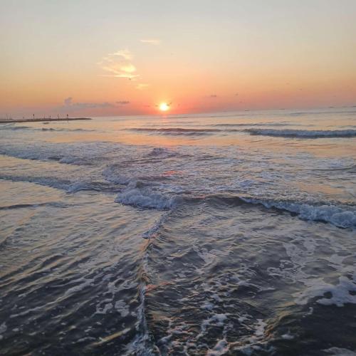 a sunset on the beach with the tide coming in at Galveston condo- walk to beach - ocean view - 2 pools in Galveston