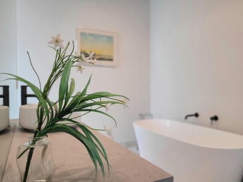 a bathroom with a vase with a plant on a counter at Hosts on the Coast Skippers Landing in Whitianga