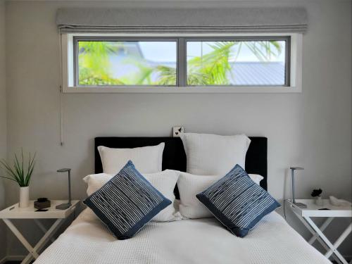 a bedroom with a bed with blue and white pillows at Hosts on the Coast Skippers Landing in Whitianga
