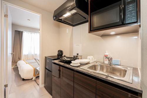 a kitchen with a sink and a microwave at Mi-Hotel Kitashinjuku 北新宿 in Tokyo