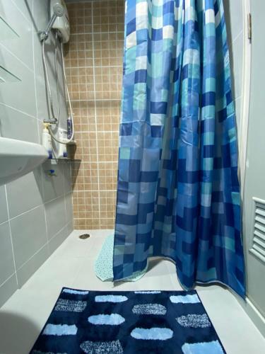 een badkamer met een blauw douchegordijn en een blauw tapijt bij LPN Seaview Cha-am in Ban Phu Wai
