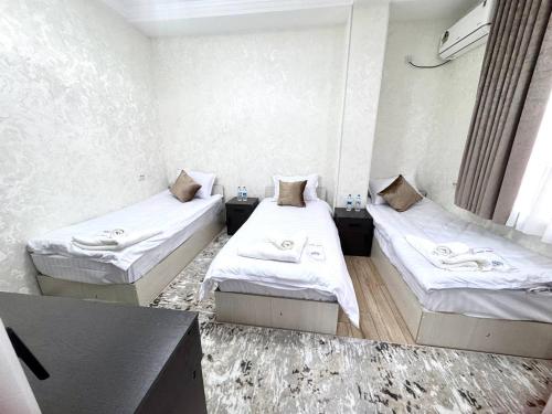 ein Zimmer mit zwei Betten und einem Tisch darin in der Unterkunft Sunnat guest house in Buxoro