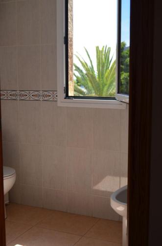 a bathroom with a window and a toilet and a sink at Apartamento Atis Tirma in Gran Tarajal