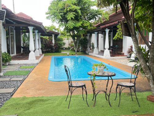 a table and chairs in front of a swimming pool at Excellence Pool Villa in Na Jomtien