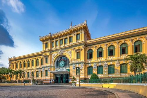 a large yellow building with palm trees in front of it at Mandarest Hsaa 32 in Ho Chi Minh City