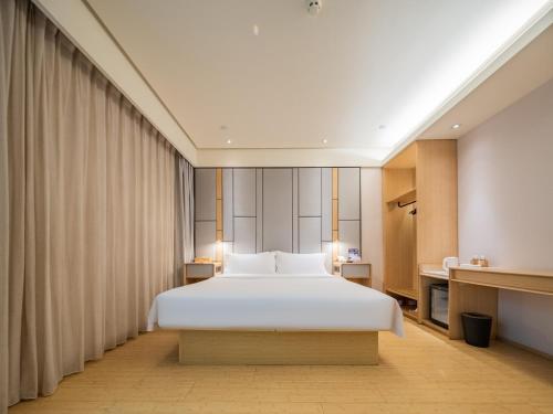 una camera da letto con un grande letto bianco in una stanza di JI Hotel Chengdu Tianfu Square a Chengdu