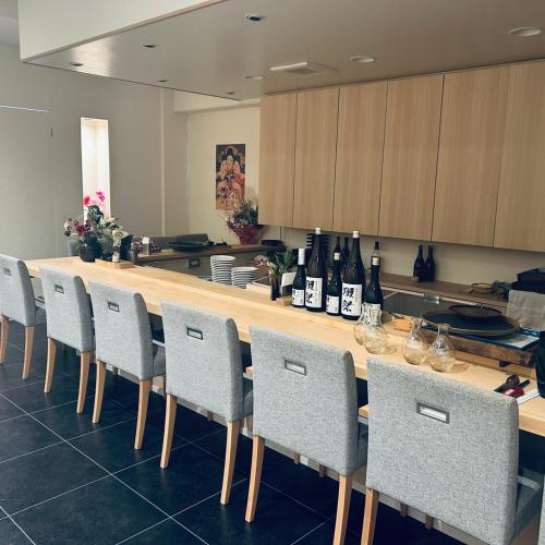 a kitchen with a bar with chairs and bottles of wine at Fujisansuikan Kawaguchiko 富士山水館 in Fujikawaguchiko