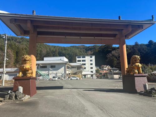 a pavilion with two lion statues in a parking lot at ホテル富士山水館富士山一望河口湖車で3分 in Fujikawaguchiko