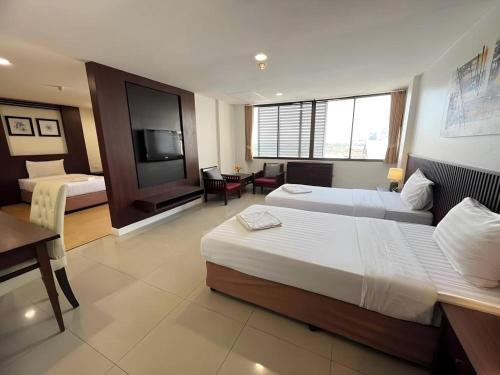 a hotel room with two beds and a television at Laemchabang City Hotel in Ban Thung Sukla