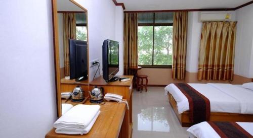 ein Hotelzimmer mit zwei Betten und einem Spiegel in der Unterkunft PC Palace Hotel in Sakon Nakhon