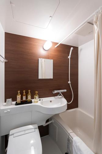 a bathroom with a sink and a toilet and a bath tub at 伊万里リバティホテル in Imari