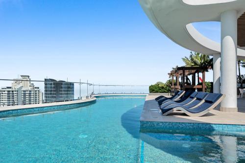 a pool at a resort with blue chairs and the ocean at The Gallery Residences Broadbeach - Official Listing in Gold Coast