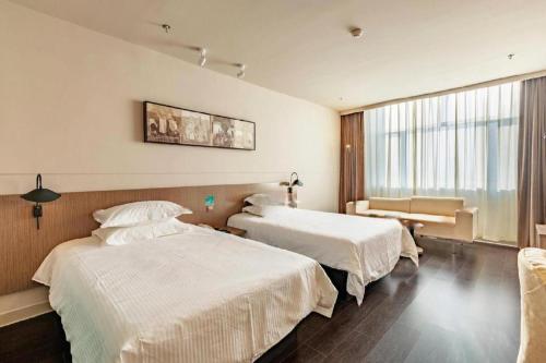ein Hotelzimmer mit zwei Betten und einem Fenster in der Unterkunft Jinjiang Inn Select Hohhot Chengjisihan Square Metro Station in Hohhot