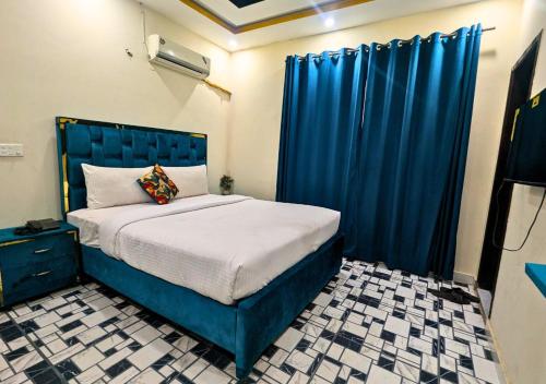 Schlafzimmer mit blauem Bett und blauen Vorhängen in der Unterkunft Hayat Lodges & Hotel in Lahore