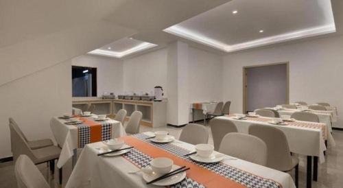 a room with white tables and chairs and a kitchen at JTOUR Inn Wuhan Wusheng Road Metro CapitaLand Plaza in Wuhan