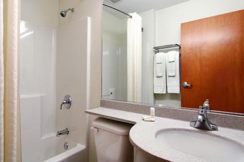 a bathroom with a sink and a toilet and a mirror at Microtel Inn & Suites by Wyndham Bridgeport in Bridgeport