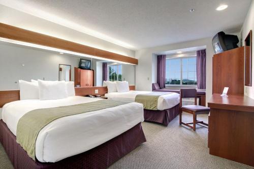 a hotel room with two beds and a desk at Microtel Inn & Suites by Wyndham Bridgeport in Bridgeport