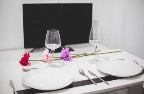 una mesa con dos platos blancos y dos copas de vino en Apartamento Almendra BAJO, en Ronda