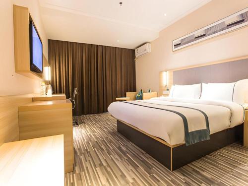 a hotel room with a large bed and a flat screen tv at City Comfort Inn Nanning Mingxiu East Road Shishan Park Metro Station in Nanning
