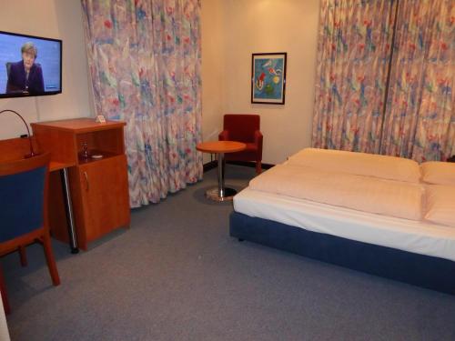 a hotel room with a bed and a desk and a tv at Astoria Hotel in Ratingen