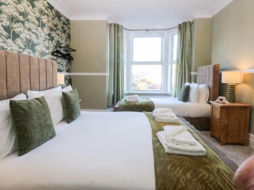 a hotel room with two beds and a window at Canning Lodge in Colwyn Bay