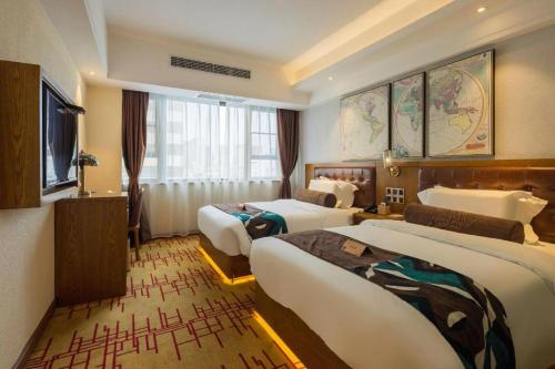 ein Hotelzimmer mit zwei Betten und einem Fernseher in der Unterkunft James Joyce Coffetel Kunming Railway Station Huancheng Nan Road Metro Station in Kunming