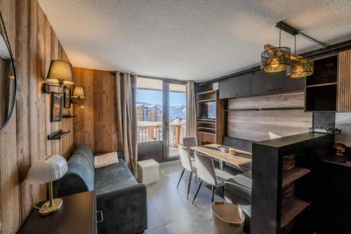 a living room with a couch and a dining room table at Val Thorens Cosy Pieds des pistes Centre Val Thorens 2 chbres in Val Thorens