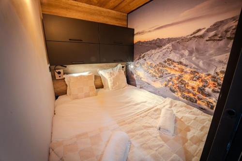 a large bed in a room with a painting on the wall at Val Thorens Cosy Pieds des pistes Centre Val Thorens 2 chbres in Val Thorens