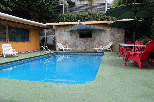 una piscina con sillas, una mesa y sombrillas en Hostal Cocos Inn, en Panamá