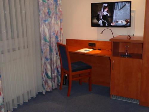 a room with a desk with a chair and a television at Astoria Hotel in Ratingen