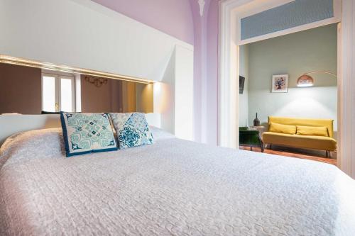 une chambre avec un grand lit blanc avec des oreillers bleus dans l'établissement Palazzino San Francesco, à Catane