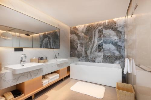 Un baño con dos lavabos y una bañera. en Zhangjiajie Valley Secret Resort, en Zhangjiajie