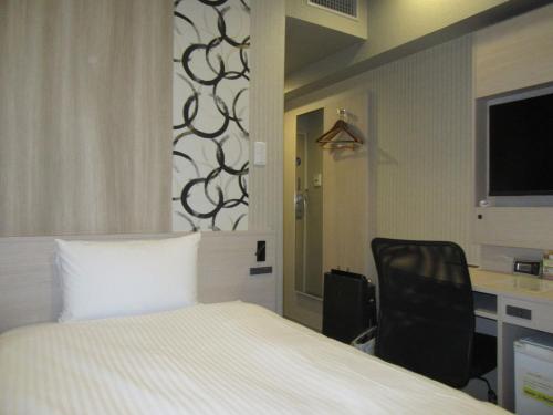 a bedroom with a bed and a desk and a chair at Smile Hotel Hachinohe in Hachinohe