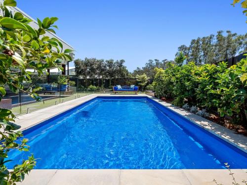 a swimming pool with blue water in a yard at The Doggy Beach House - with Pool in Pottsville in Pottsville
