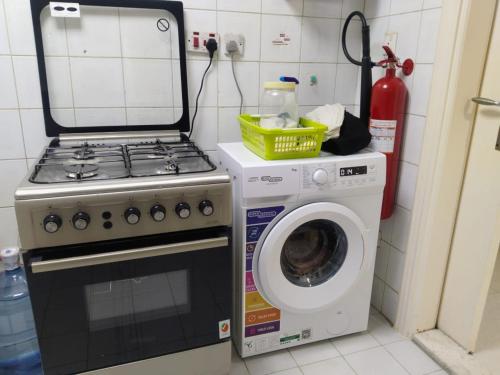 a kitchen with a stove and a washing machine at thrifty regular room for 2 to 4 in Abu Dhabi