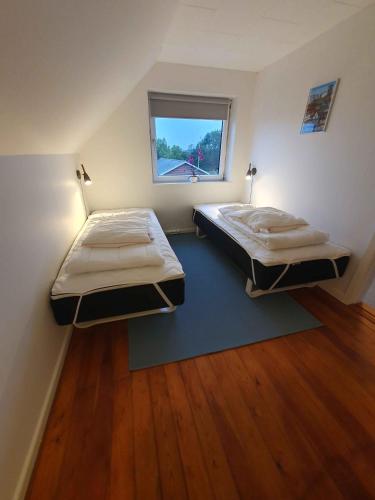 Dos camas en una habitación pequeña con ventana. en Lovely Holiday Home With Views Of Fields, en Lebøl