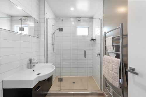 a white bathroom with a sink and a shower at The City Retreat in Christchurch