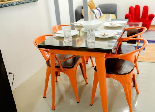 a dining room table with orange chairs and a black table at Clark Stays Yellow in Iba