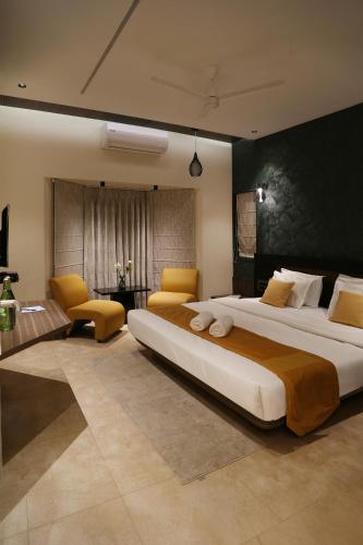 ein großes Schlafzimmer mit einem großen Bett und gelben Stühlen in der Unterkunft Hotel The Leaf in Aurangabad